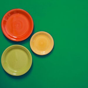Still life - vermelho, verdes e amarelos pratos à beira de um fundo verde